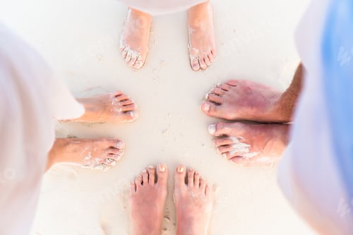 Preview: Close-up of the feet of family on the white sandy beach