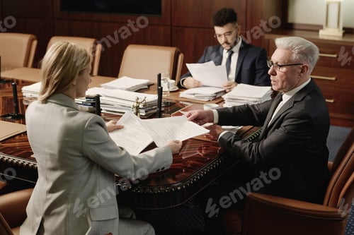 Preview: Biracial Group of Attorneys Working with Documents Sitting at Office Table