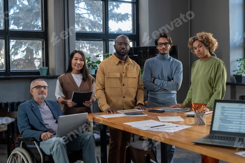 Preview: Group of multiracial colleagues standing by table in boardroom