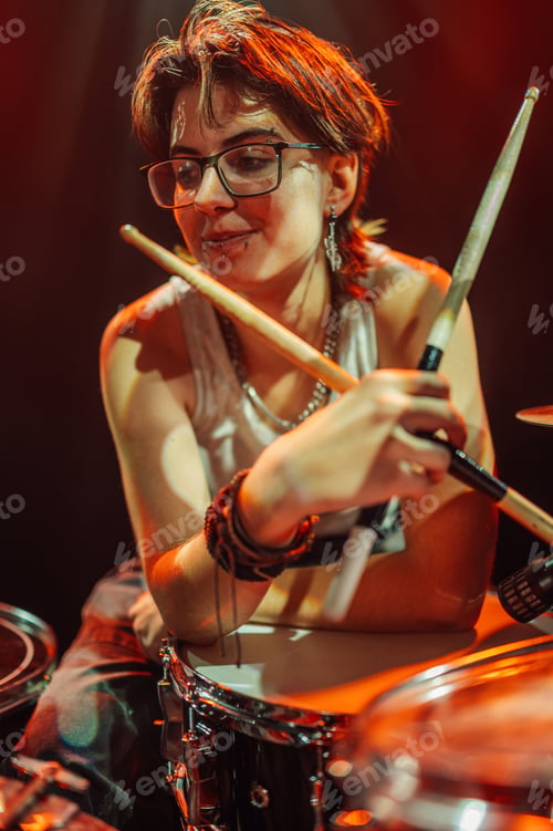 Preview: Female drummer performing live on stage with drumsticks