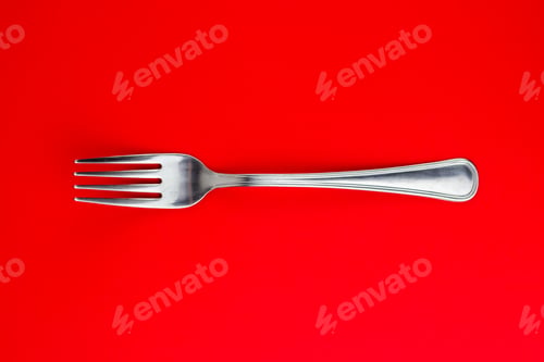 Preview: Top shot of a silver fork on a bright red background.