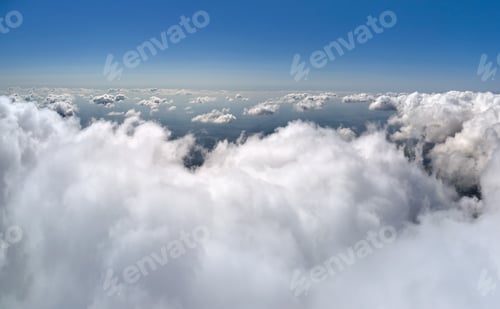 Preview: Aerial view from airplane window at high altitude of earth covered with white puffy cumulus clouds.