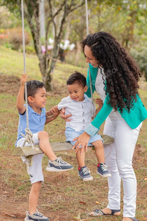 Preview: Joyful Mother Playing with Two Young Sons on a Wooden Swing in the Park