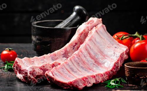 Preview: Raw ribs with spices and tomatoes on the table.