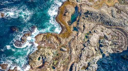 Preview: Aerial view of rugged coastline and turquoise waves.