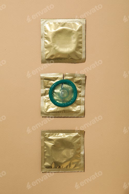 Preview: Condoms in a golden wrapper on a light background close-up