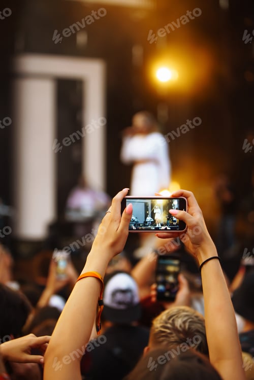 Preview: Hand with a phone records live music festival. People taking photographs with smart phone.