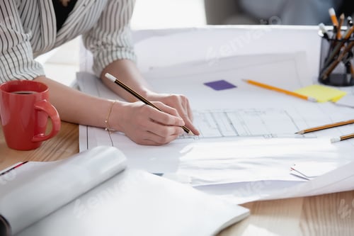 Preview: Cropped shot of businesswoman using pencil during work with blueprints
