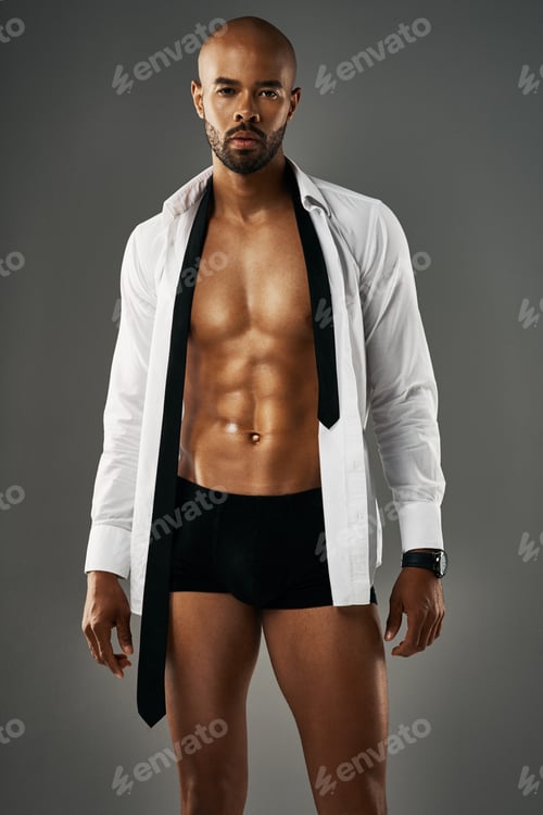 Preview: Studio portrait of a sexy young man showing off his abs against a gray background