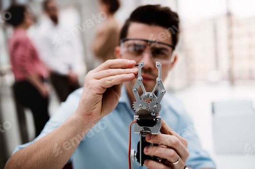 Preview: A young businessman or scientist with robotic hand standing in office, working.