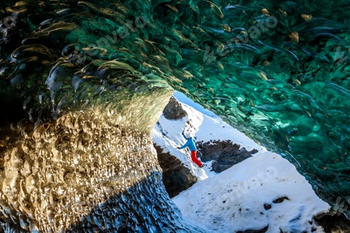Preview: View through glacial ice cave with climber in the background.