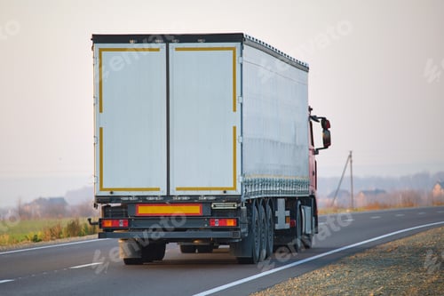 Preview: Semi-truck with cargo trailer driving on highway hauling goods in evening. Delivery transportation