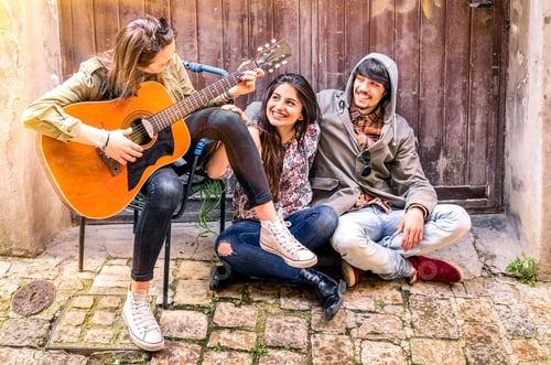 Preview: Group of teenager friends having fun playing guitar