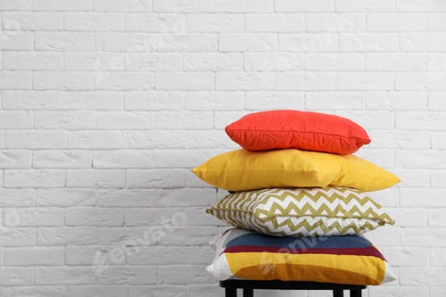 Preview: Many different pillows on chair near brick wall with space for text