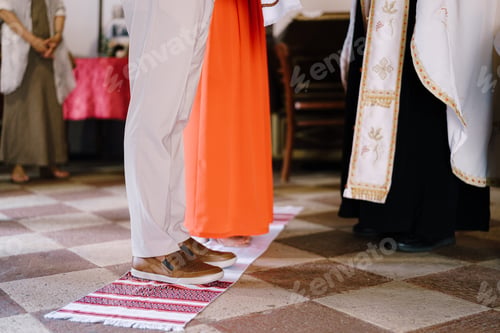 Preview: Bride and groom stand on an embroidered towel in front of the priest. Close-up