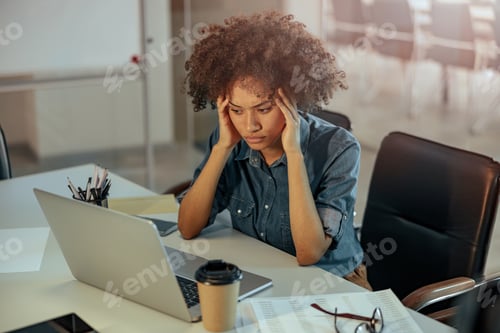 Preview: Busy Afro American lady working with laptop in the office