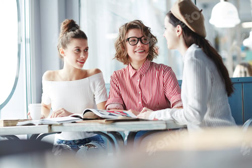 Three Young Women Chatting at Cafe Table