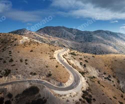 Preview: Aerial view of winding mountain road, blue sky at sunrise