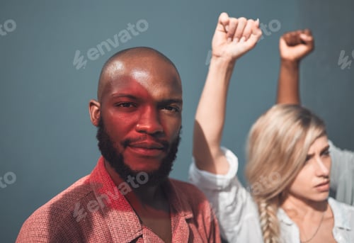 Preview: Portrait of young, african american man standing together with protesters, holding fists, showing