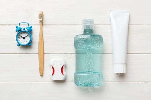Preview: Mouthwash and other oral hygiene products on colored table top view with copy space