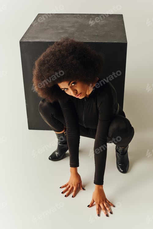Preview: beautiful african american female model in black bodysuit posing next to black cube, fashion concept