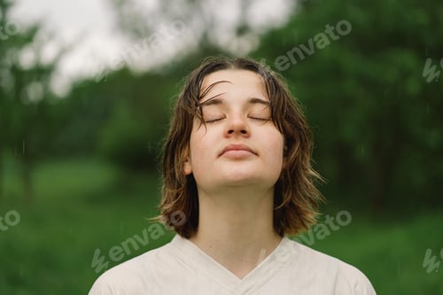 Preview: Cheerful Teen Girl With Pronounced Face From Sprayed Small Splashes Warm Summer Rain In Outdoors.