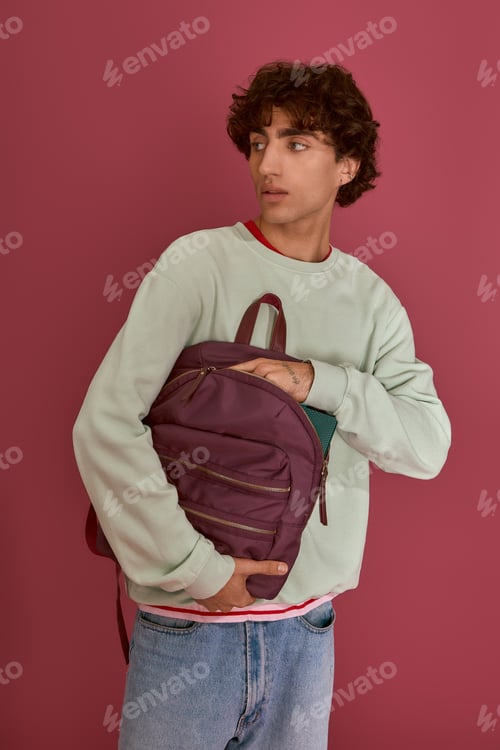 Preview: Stylish young man poses with a trendy backpack against a vibrant background