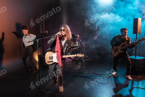 Preview: Male singer with microphone and rock and roll band performing hard rock music on stage