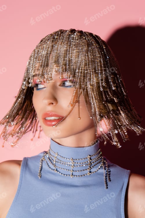 Preview: Motion blur of stylish woman in jewelry headwear looking away on pink background