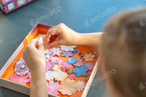 Preview: Small, colorful paper flowers in child hands, little girl creativing of 3D flowers. Child