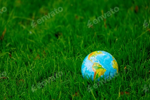 Preview: Earth globe on green grass with autumn leaves