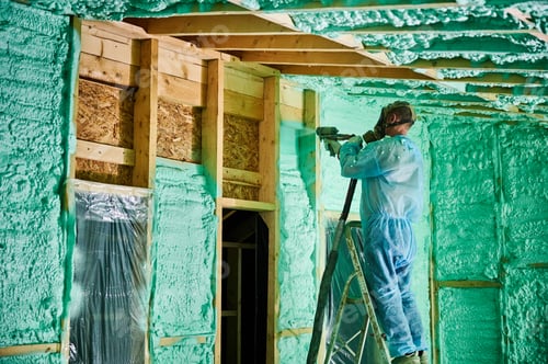 Preview: Worker spraying polyurethane foam for insulating wooden frame house.