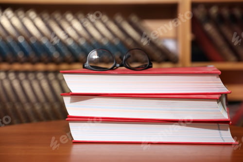 Preview: Stack of books and glasses on table in library