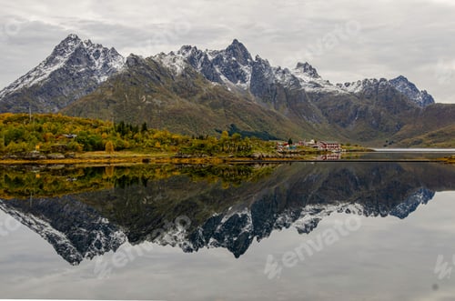 Preview: Scenic view of a lake surrounded by snowcapped mountains on a cloudy day