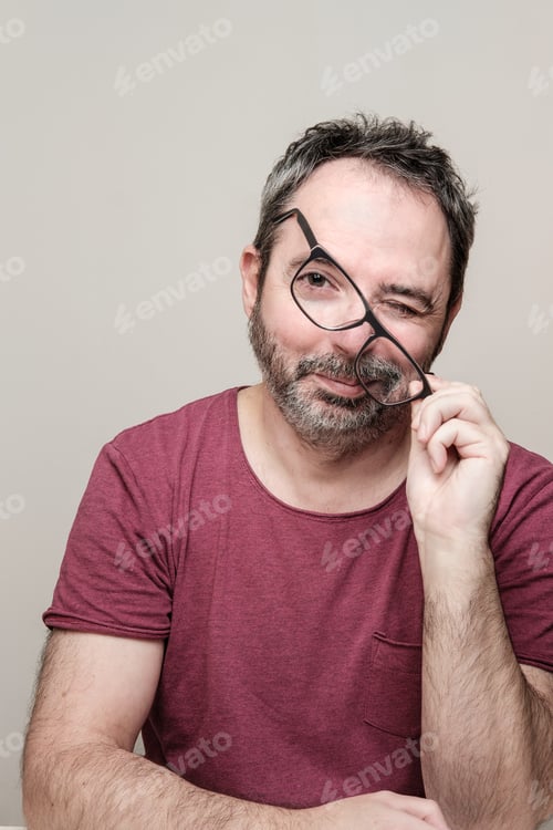 Preview: Portrait of a smiling mature man with beard wearing red t-shirt and glasses.