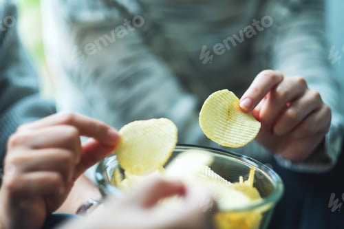 Preview: Closeup image of friends sharing and eating potato chips at home party