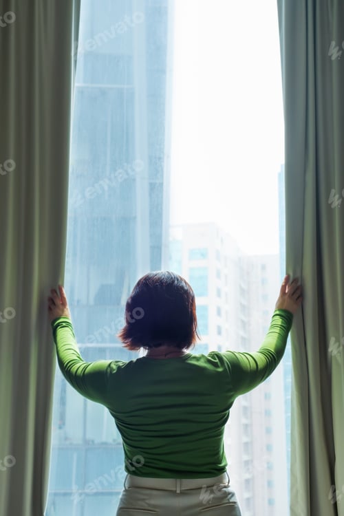Preview: A woman opens curtains and looks out window.
