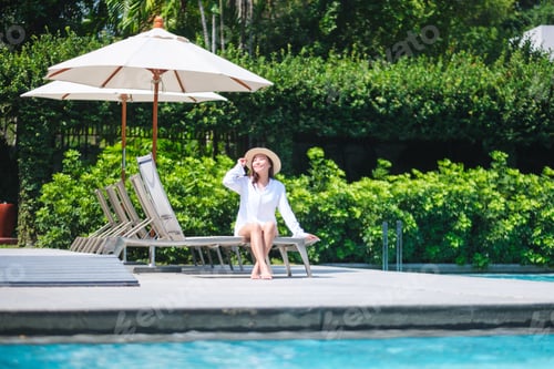 Preview: Portrait image of a woman with hat sitting and relaxing by the swimming pool
