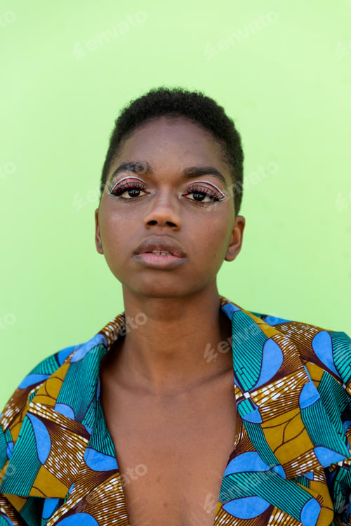 Preview: Young black female in traditional African suit against pistachio background