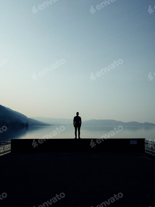 Preview: Man silhouetted against a beautiful alpine lake