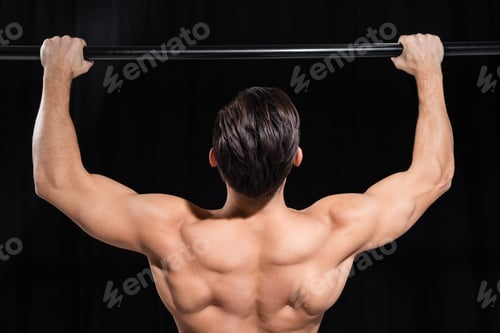 Preview: back view of muscular sportsman exercising on horizontal bar isolated on black