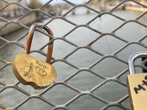 Preview: Closeup of love padlocks on a chain link fence with a river in the background