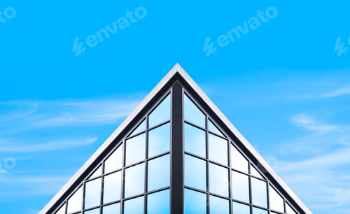 Preview: Symmetry and low angle view of glass office building in industrial loft style against blue sky