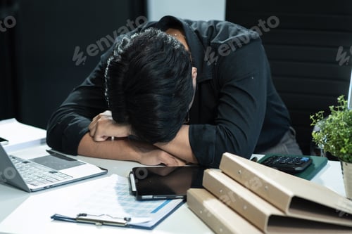 Preview: Young stressed Asian businessman working in the office.