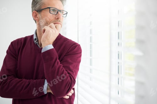 Preview: Thoughtful man looking through the window