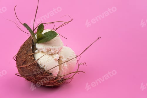 Preview: Vanilla ice cream balls in an empty coconut decorated with mint leaves on a pink background