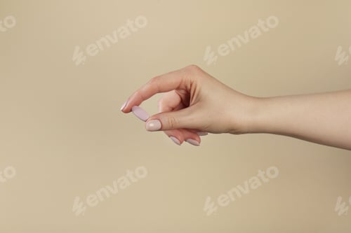 Preview: Woman holding vitamin pill on dark beige background, closeup. Health supplement