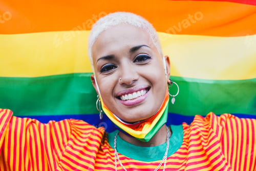 Preview: Beautiful latin woman smiling with lgbt rainbow flag in background