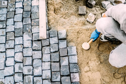 Preview: Manual labor, industrial worker laying stone pavement on sand path