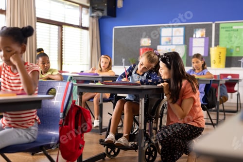 Preview: Diverse female teacher and schoolgirl in wheelchair in elementary school class